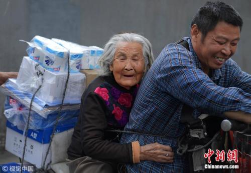 资料图：2018年4月，成都，为了尽孝谋生两不误，53岁的货郎蔡玉俊，每天驮着92岁身患老年痴呆的母亲，穿梭在成都大街小巷。 图片来源：视觉中国